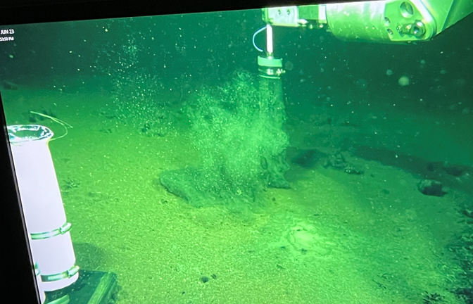 Screenshot from the ROV control room. Here you can see the ROV arm collecting a sediment core from deep within Orca Basin (>2400 m depth).